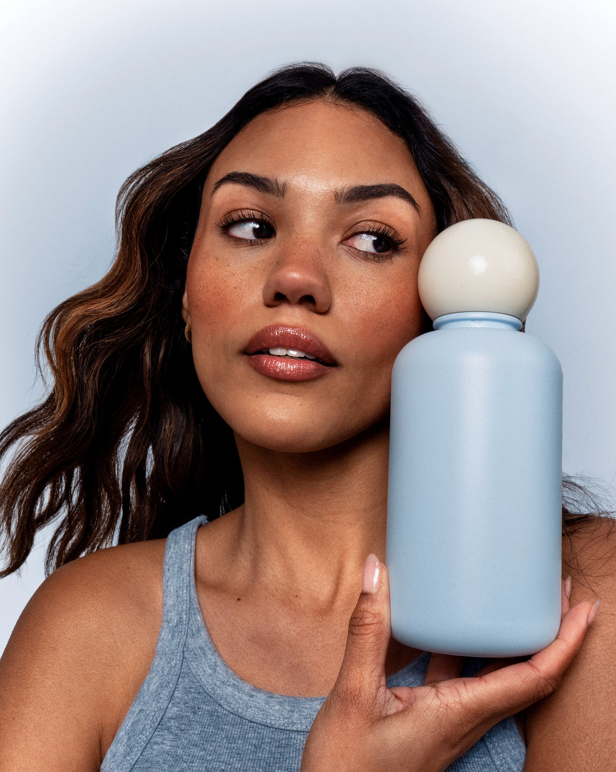 Woman holding Alice luxury water bottle in pale blue stainless steel with white cap
